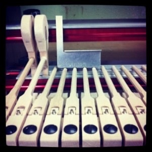 Piano hammers being glued onto shanks in the shop with a small square. 